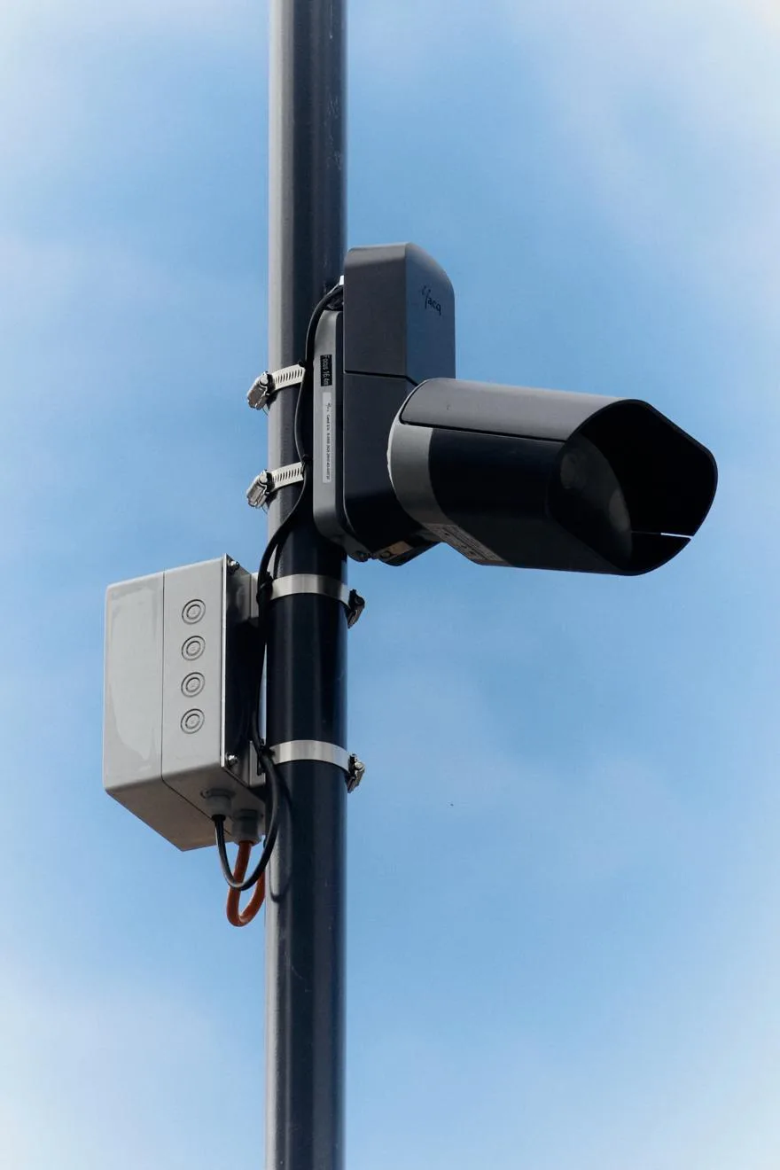 Diese Kamera zeichnet auf, wenn jemand den Bahnübergang passiert, während das Wechselblinklicht eingeschaltet ist. Eine Kamera ist an einer Säule befestigt.